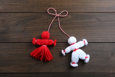 Photo of Traditional martisor shaped as man and woman on wooden background, top view. Beginning of spring celebration
