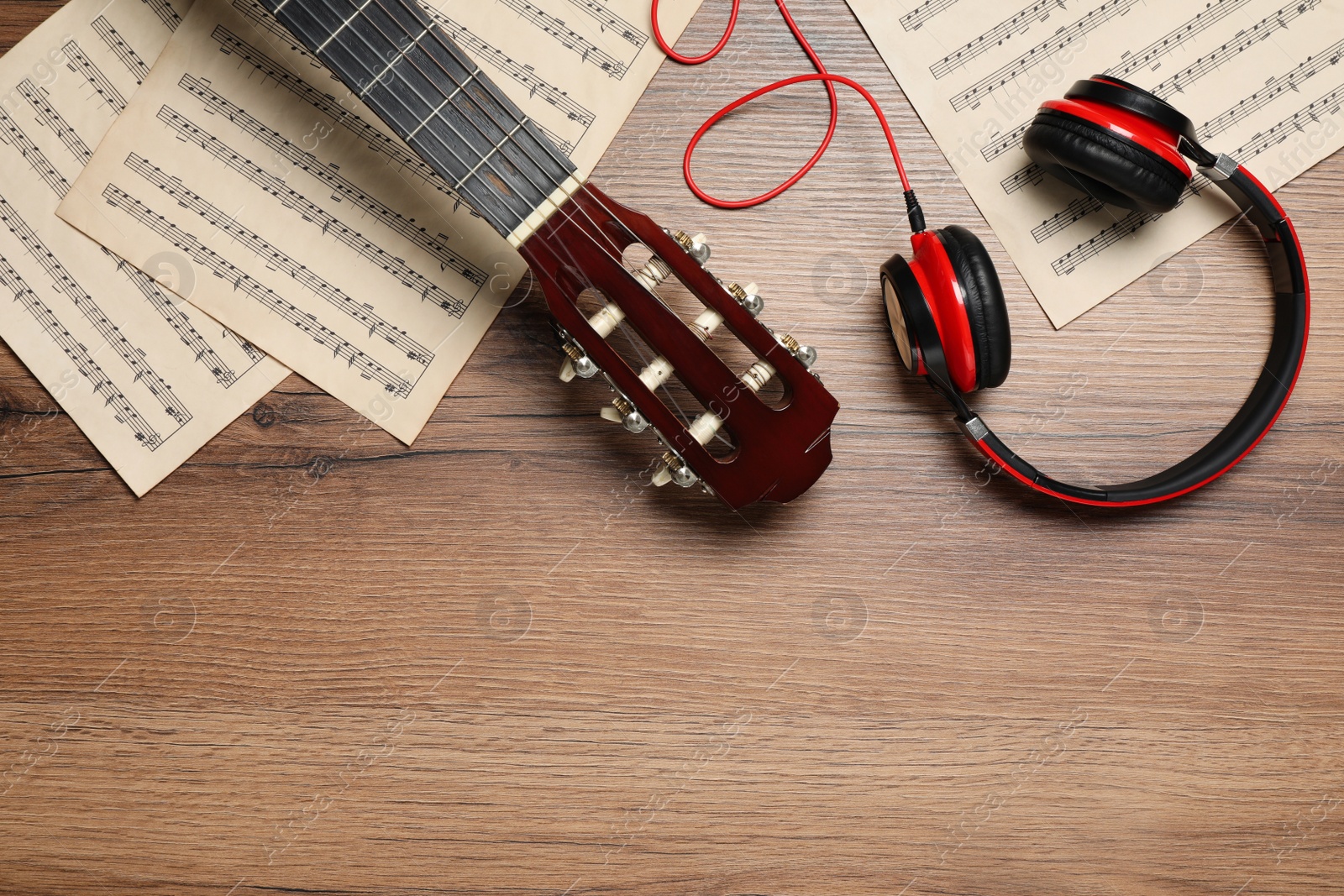 Photo of Composition with guitar and music notations on wooden table, flat lay. Space for text