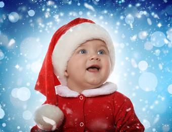 Cute baby in Christmas costume against blurred festive lights