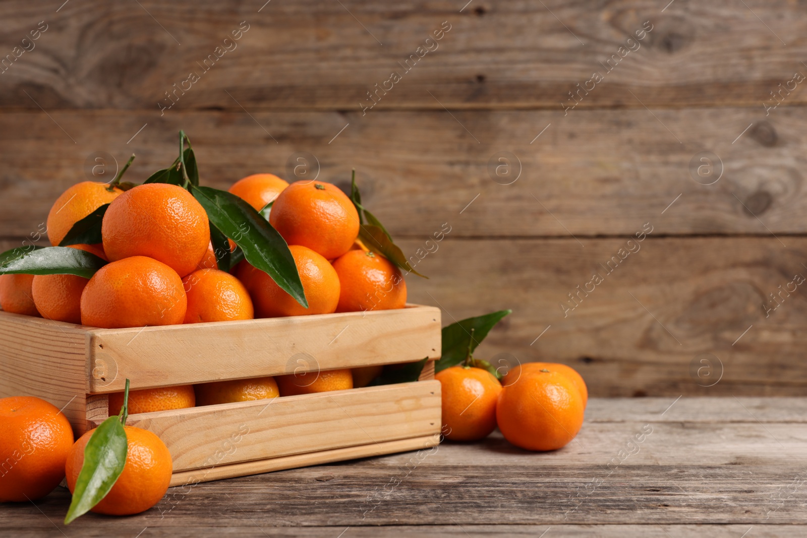 Photo of Delicious tangerines with leaves on wooden table. Space for text