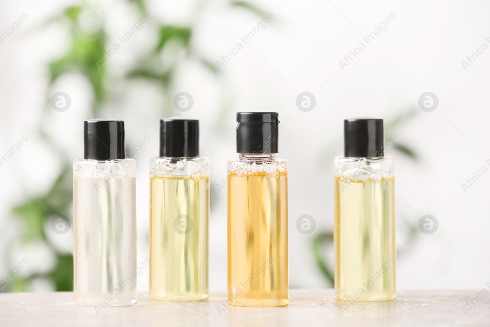 Photo of Mini bottles with cosmetic products on table against blurred background. Hotel amenities