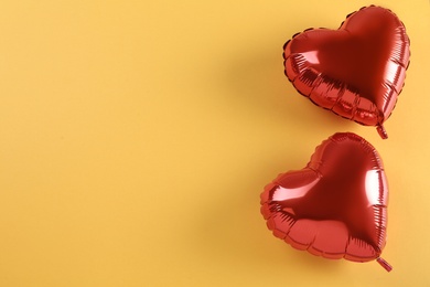 Photo of Red heart shaped balloons on yellow background, flat lay with space for text. Saint Valentine's day celebration