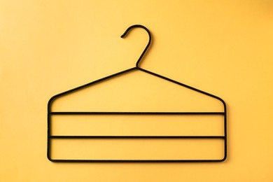 One black hanger on yellow background, top view