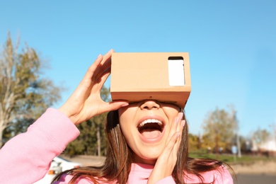 Young woman using cardboard virtual reality headset outdoors