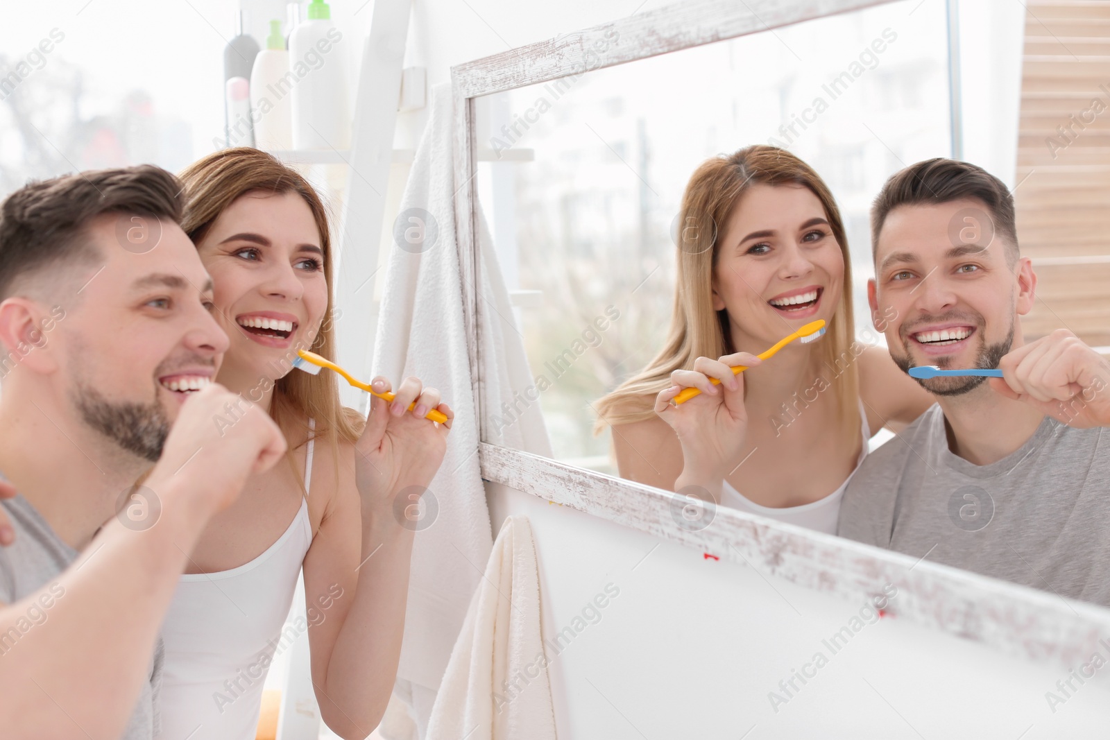 Photo of Young couple brushing teeth together in bathroom