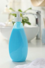 Photo of Dispenser of liquid soap on white table in bathroom