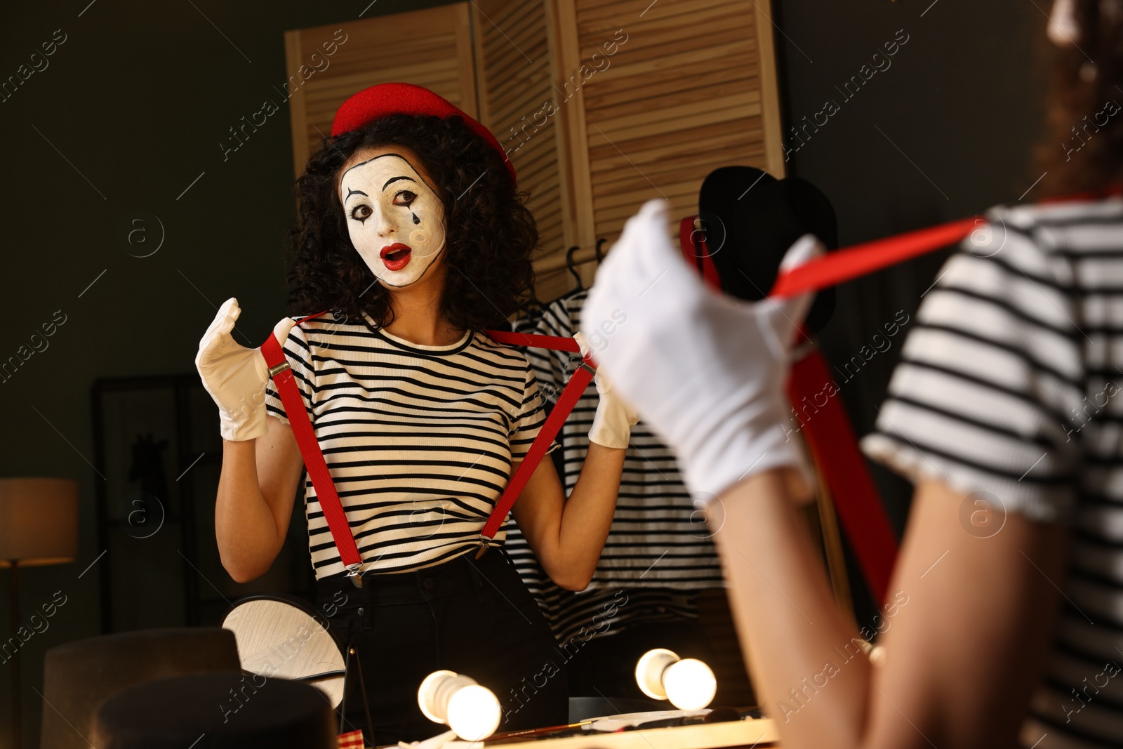 Photo of Young woman in mime costume posing near mirror indoors