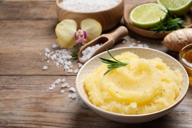 Body scrub with rosemary in bowl on wooden table, space for text