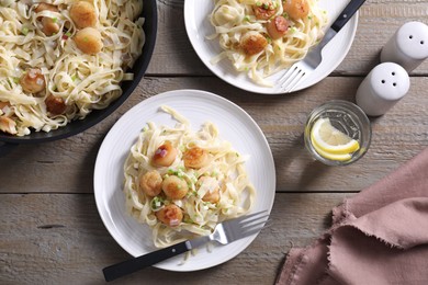 Photo of Delicious scallop pasta with onion served on wooden table, flat lay