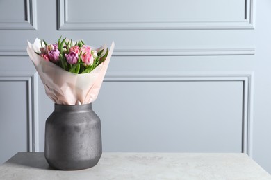 Photo of Vase with bouquet of beautiful tulips on grey table. Space for text