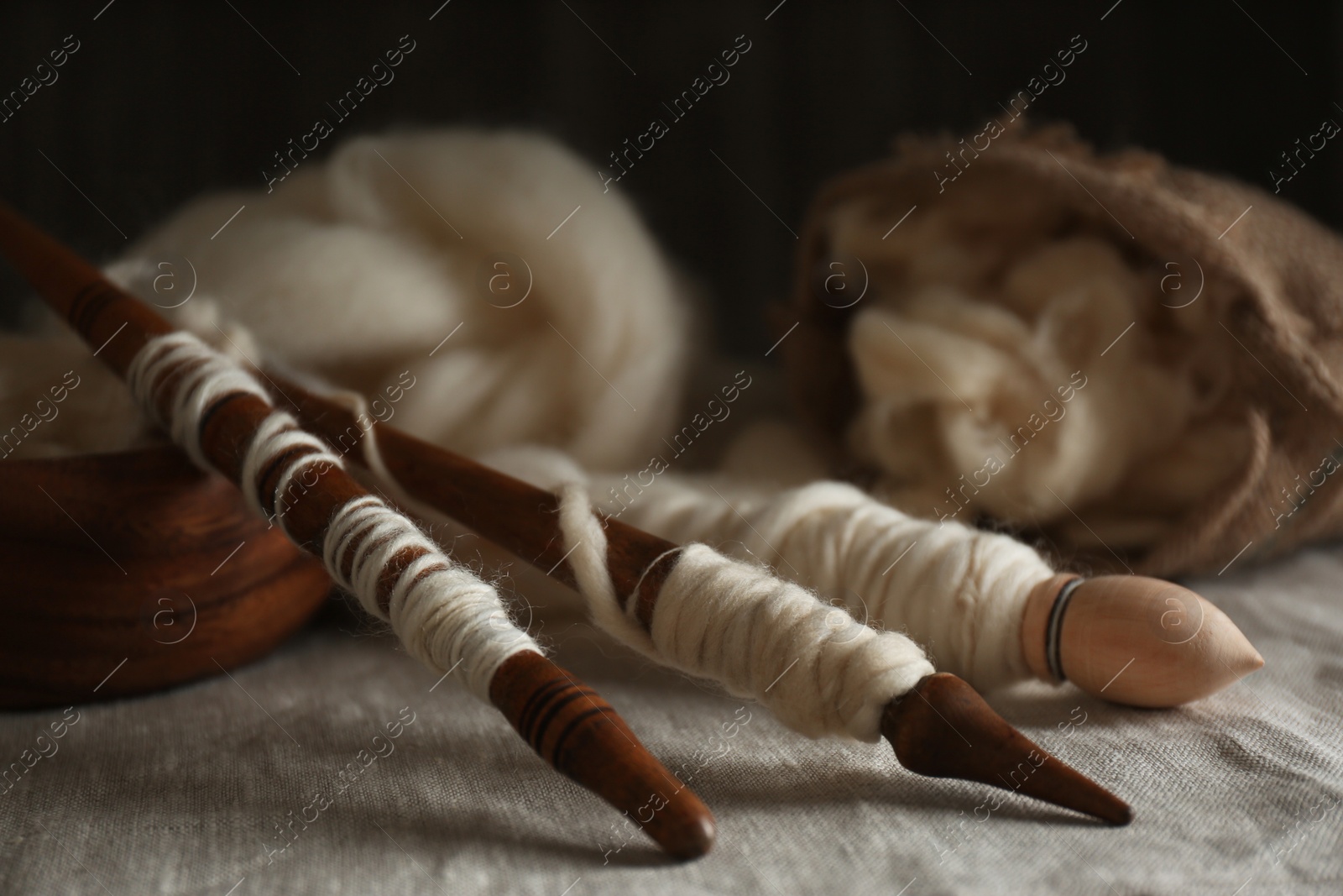 Photo of Soft white wool and spindles on table, closeup