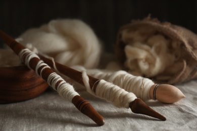 Soft white wool and spindles on table, closeup