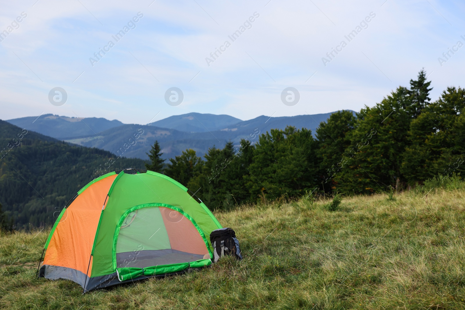 Photo of Color camping tent on grass in mountains, space for text