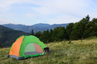 Photo of Color camping tent on grass in mountains, space for text