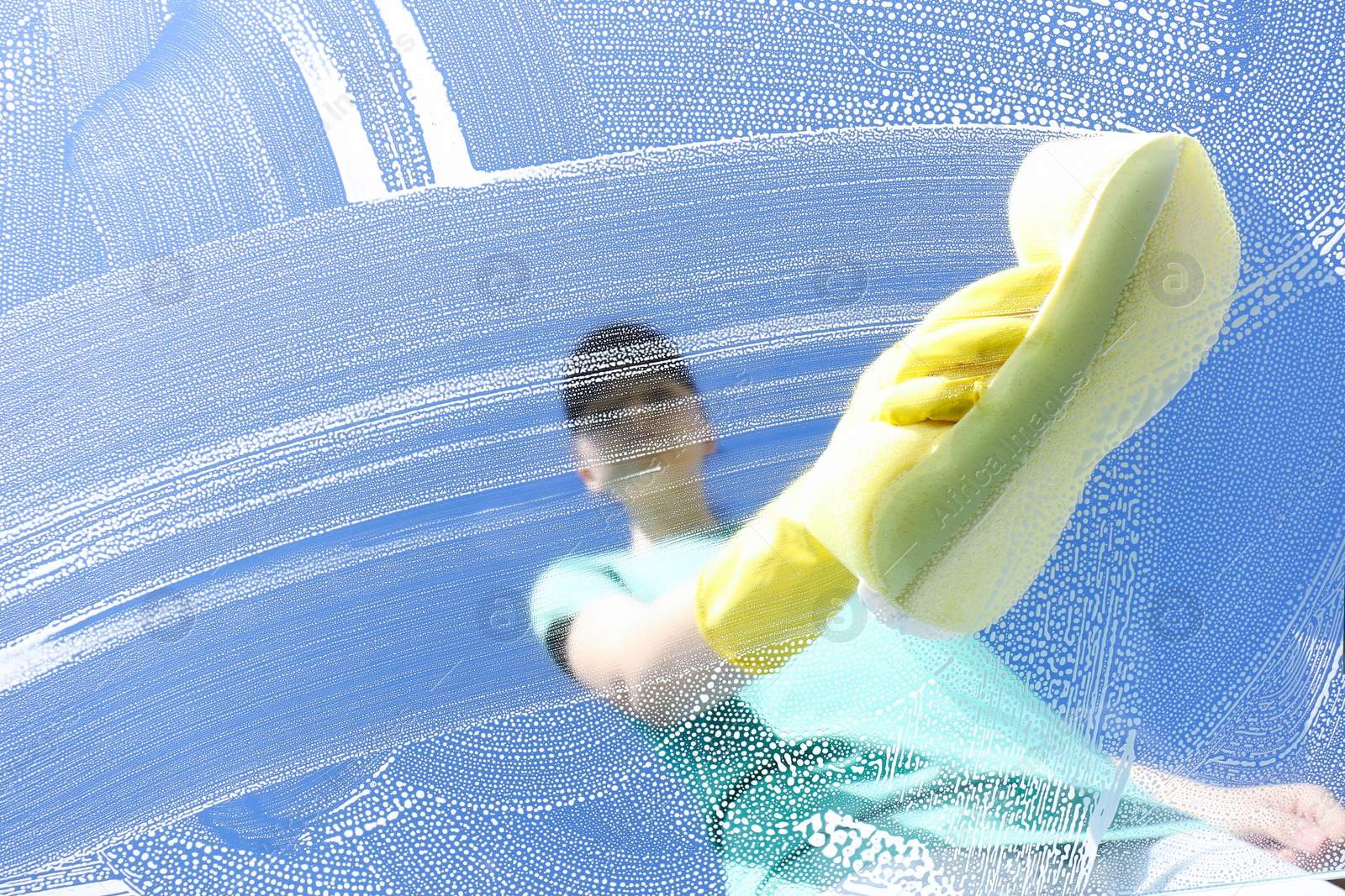 Photo of Woman cleaning glass with sponge on sunny day