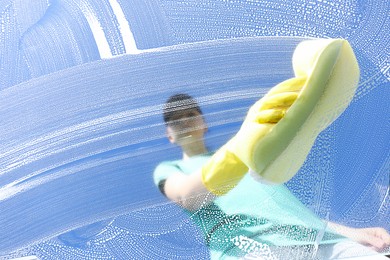 Woman cleaning glass with sponge on sunny day