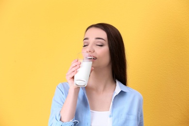 Photo of Beautiful young woman drinking milk on color background