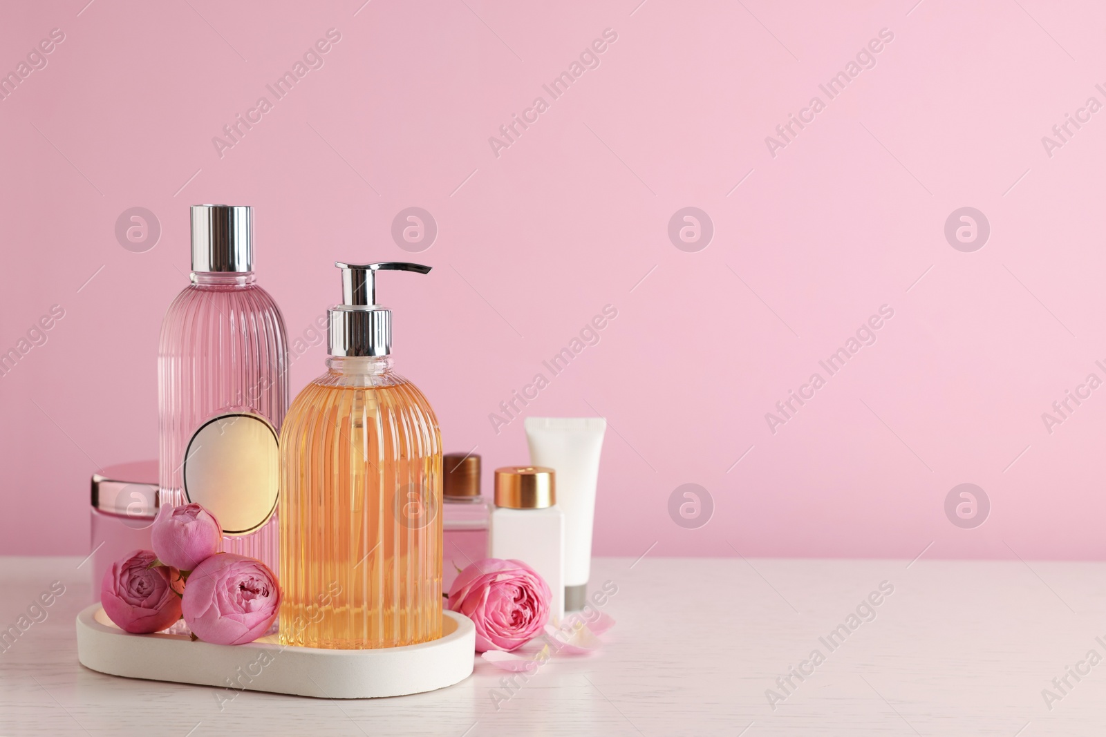 Photo of Cosmetic products and flowers on white wooden table. Space for text