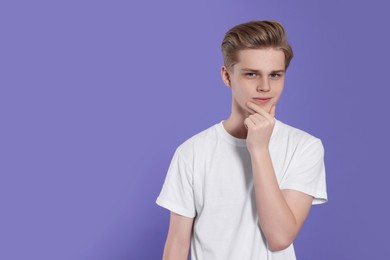 Photo of Portrait of teenage boy on purple background. Space for text