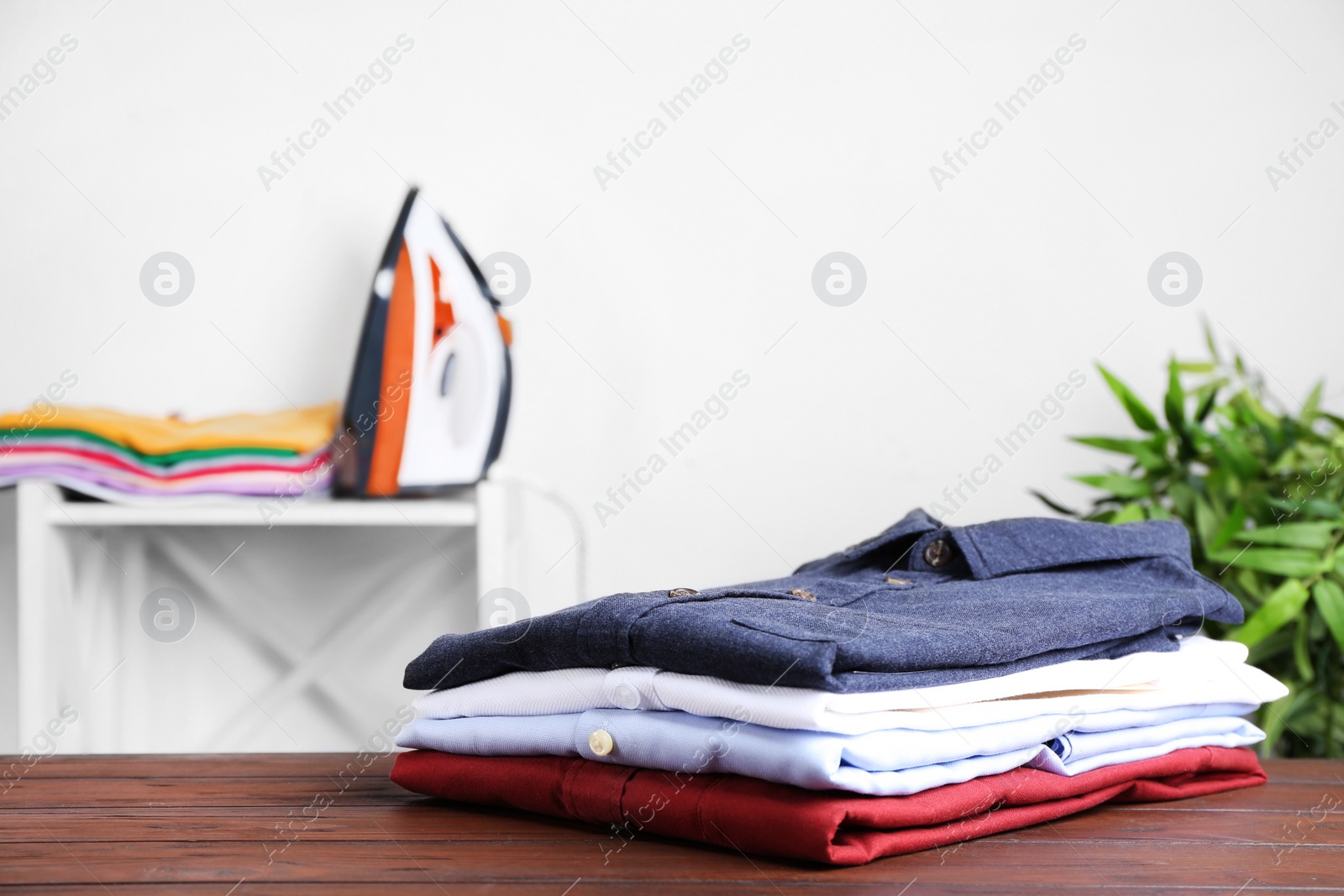 Photo of Pile of ironed clothes on table in room. Space for text