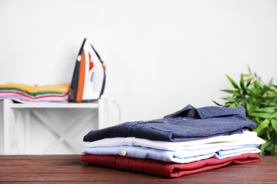 Photo of Pile of ironed clothes on table in room. Space for text