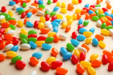 Photo of Colorful sweet jelly beans on beige background