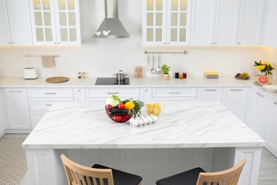 Photo of Modern kitchen interior with different products on white marble table