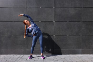 Photo of Beautiful woman in gym clothes doing exercises on street, space for text