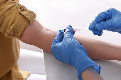 Photo of Doctor drawing blood sample of patient with syringe in hospital, closeup