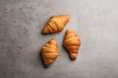 Photo of Tasty croissants on grey background, flat lay. French pastry