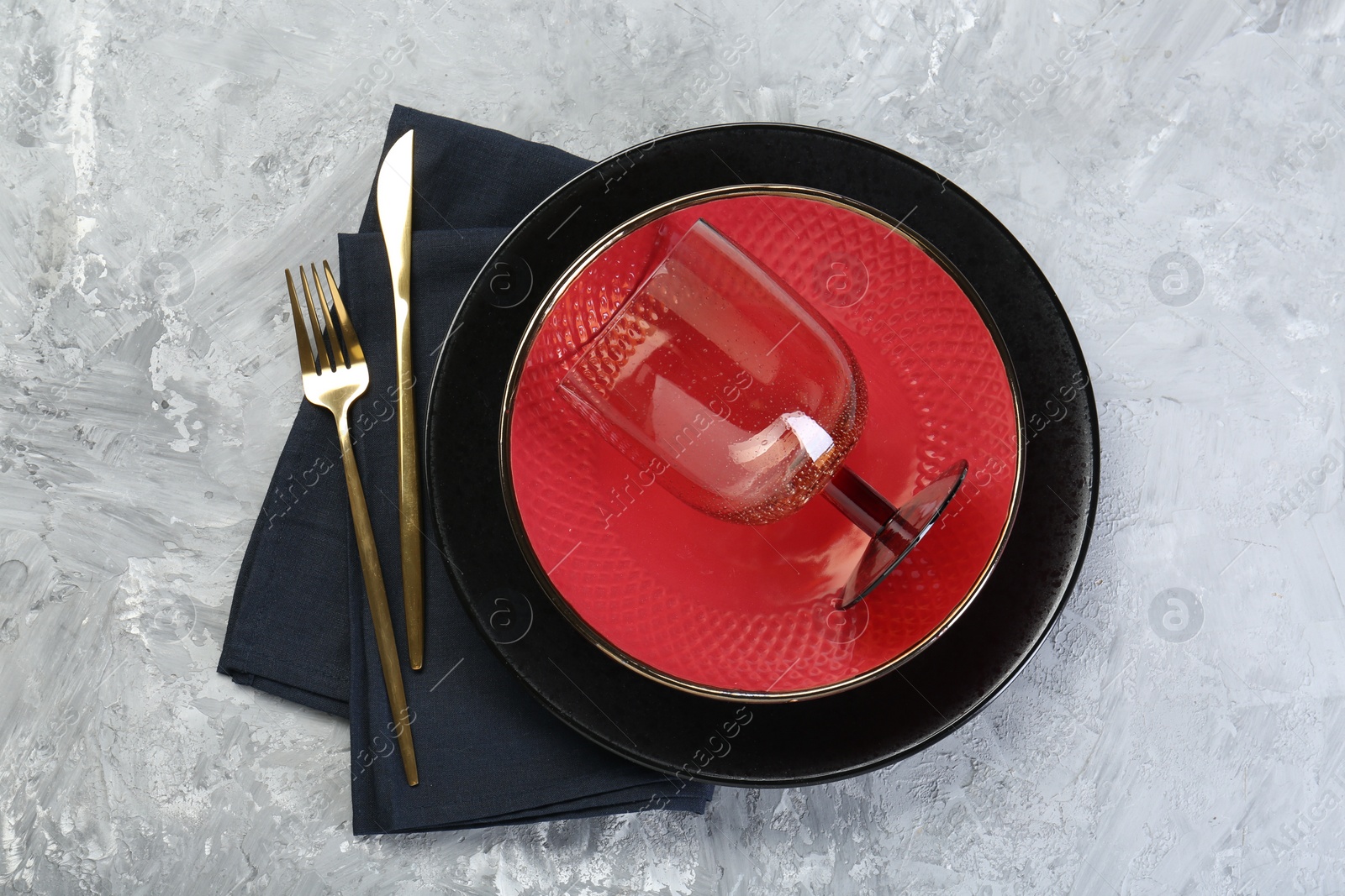 Photo of Clean plates, glass, cutlery and napkin on gray textured table, top view