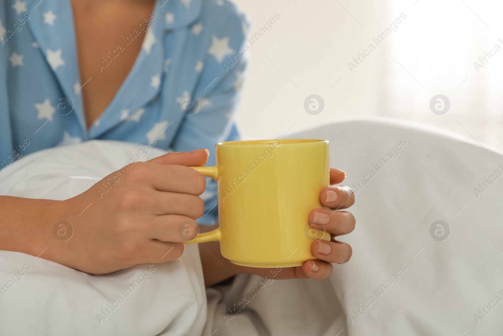 Photo of Woman with yellow cup in bed at home, closeup