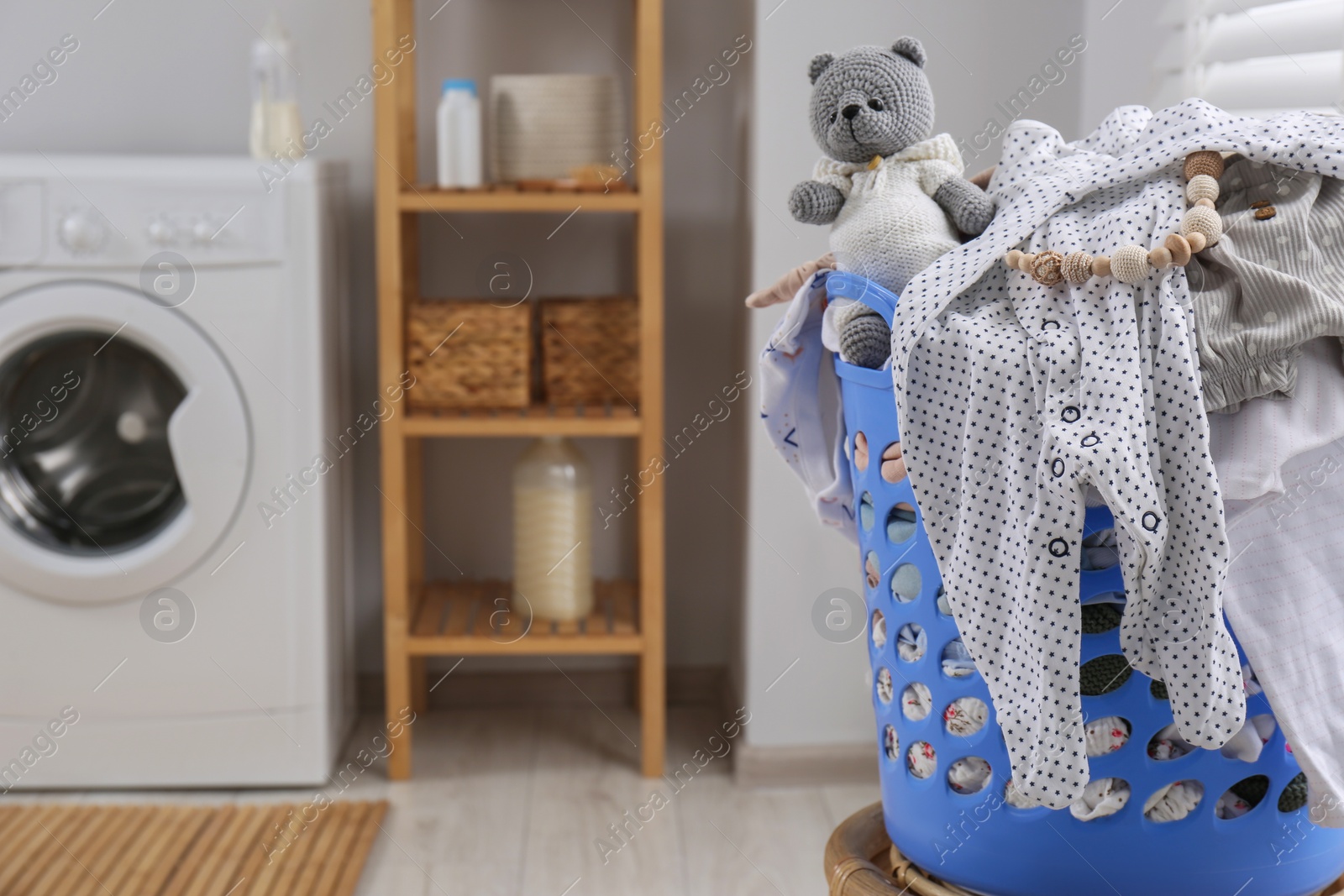 Photo of Laundry basket with baby clothes, shoes and crochet toy in bathroom, space for text