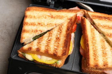 Photo of Modern grill maker with tasty sandwiches, closeup view