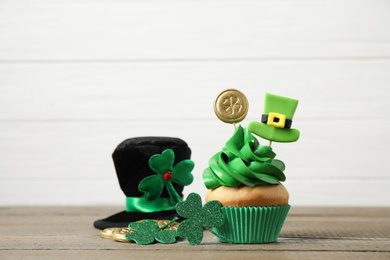 Photo of Decorated cupcake and hat on wooden table. St. Patrick's Day celebration