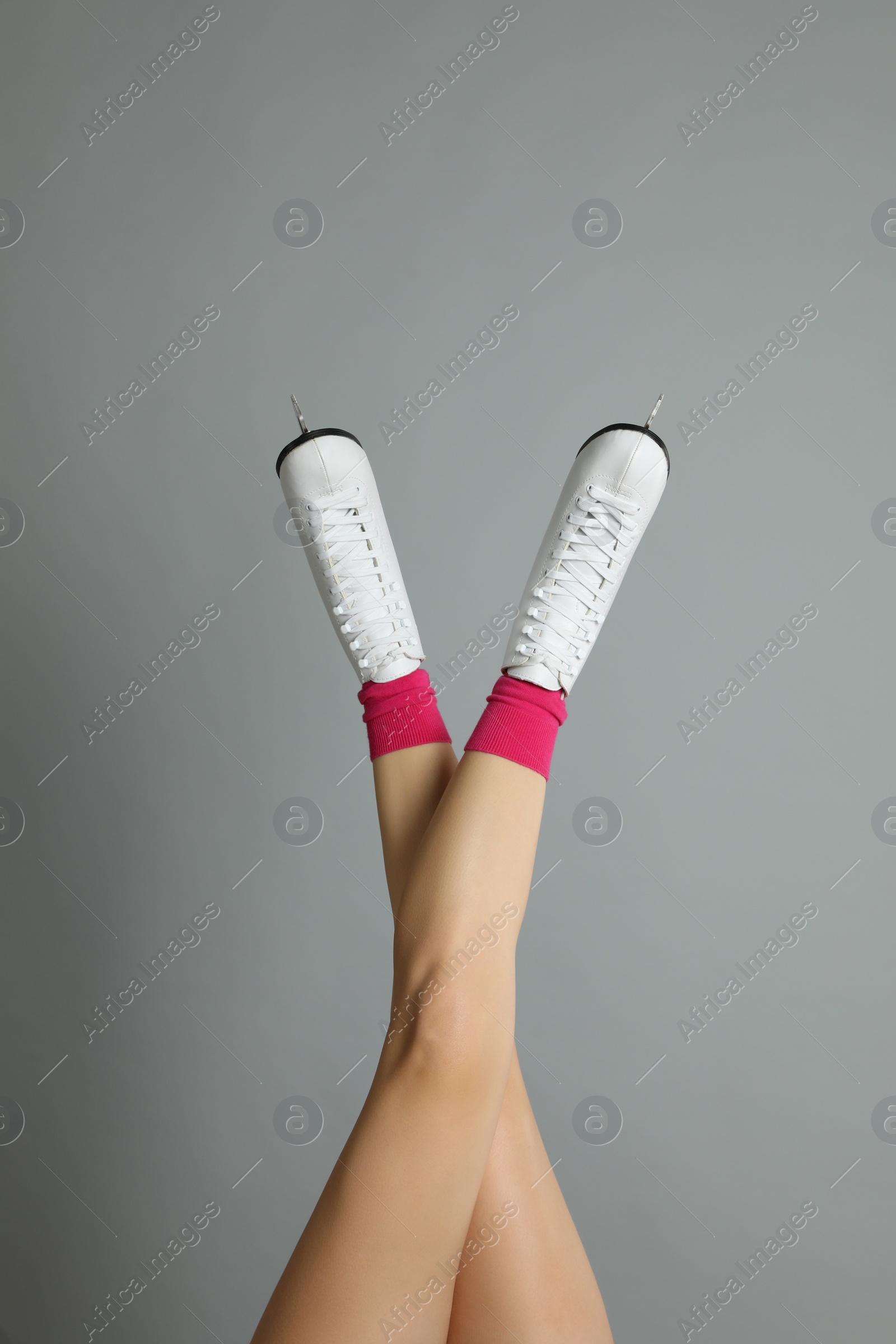 Photo of Woman in elegant white ice skates on grey background, closeup of legs