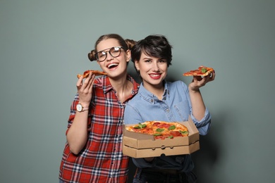 Attractive young women with delicious pizza on color background