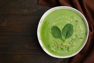 Photo of Delicious broccoli cream soup with basil and pumpkin seeds on wooden table, top view. Space for text