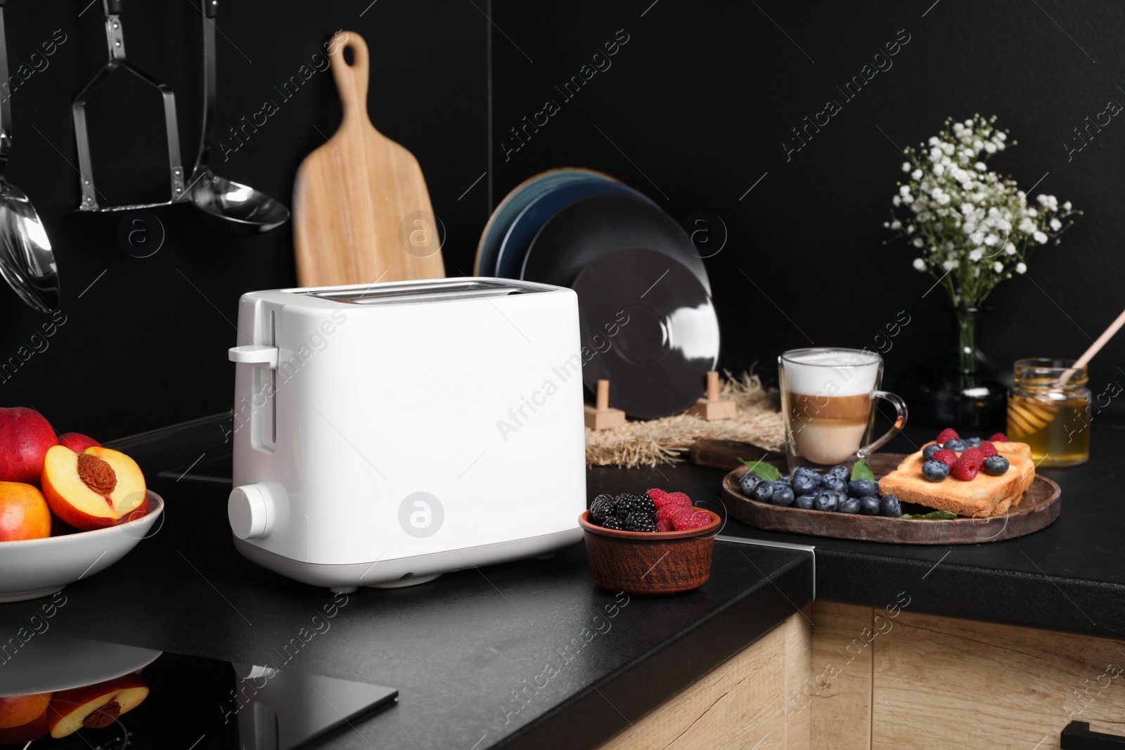 Photo of Modern toaster, bread with fresh berries and coffee on countertop in kitchen