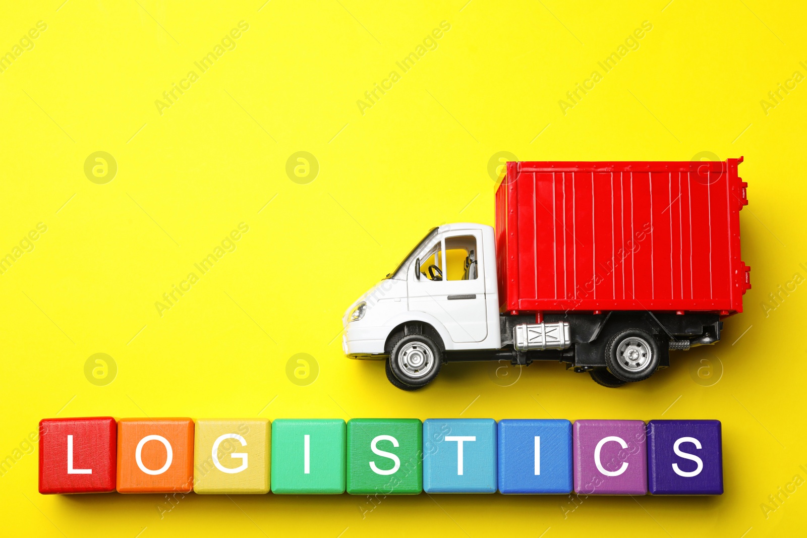 Photo of Flat lay composition with toy truck and word LOGISTICS on yellow background, space for text. Wholesale concept