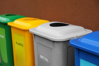 Photo of Many color recycling bins near brown wall, closeup