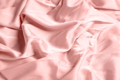 Photo of Pale pink shiny fabric as background, closeup view