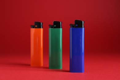 Stylish small pocket lighters on red background