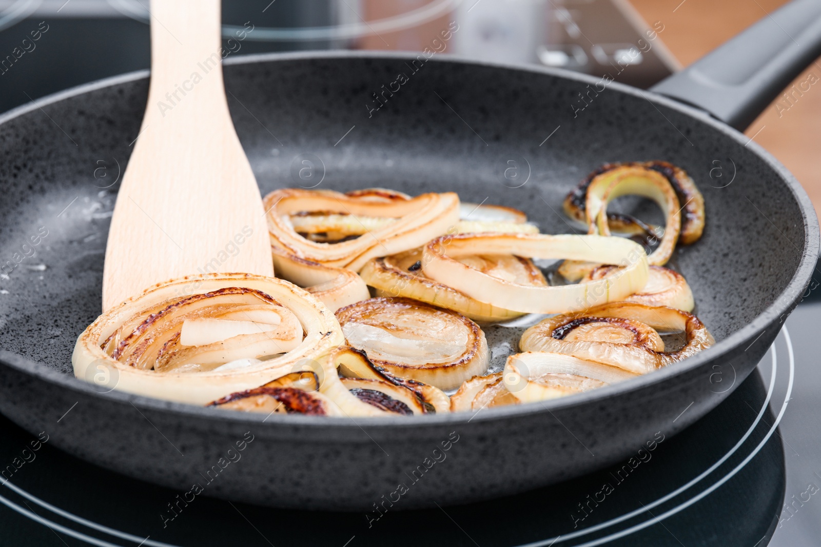 Photo of Cooking onion rings in frying pan, closeup