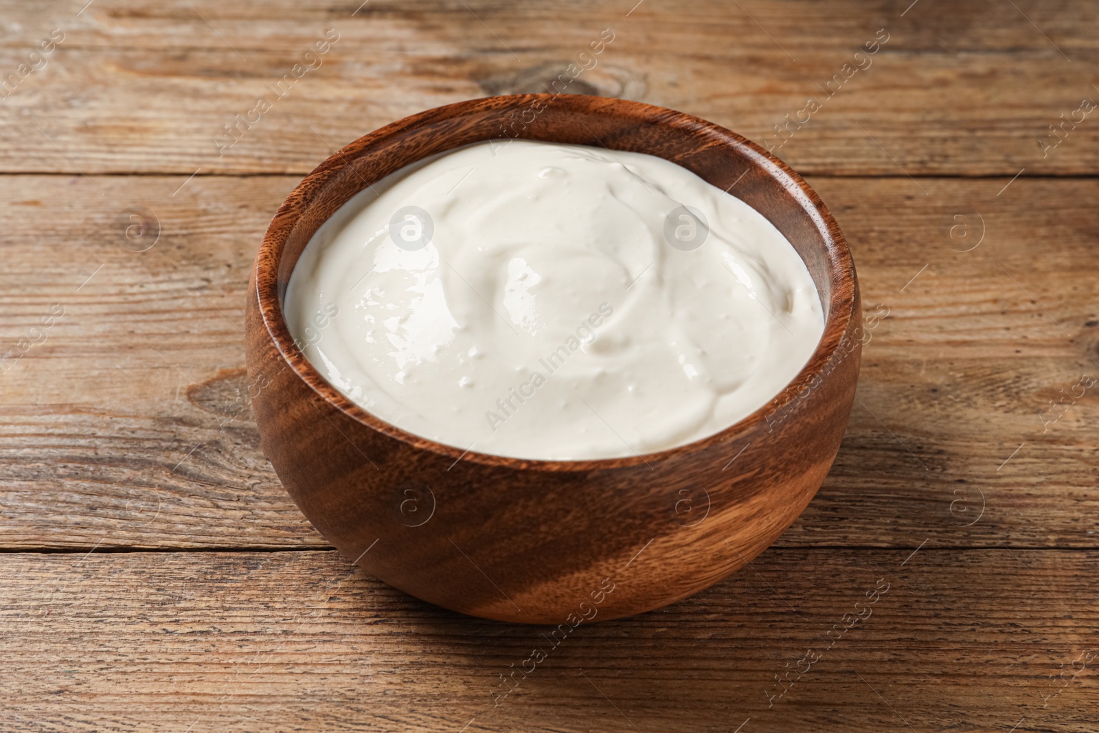 Photo of Bowl of tasty yogurt on wooden table