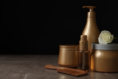 Different hair products, flower and wooden comb on grey table. Space for text