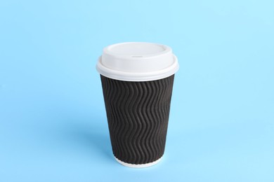 Photo of Brown paper cup with plastic lid on light blue background. Coffee to go