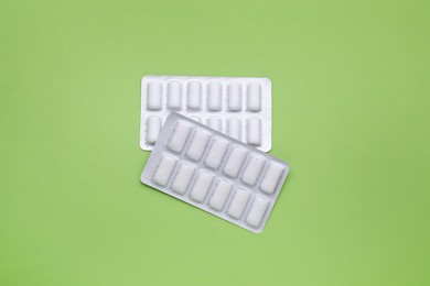 Photo of Blisters with chewing gums on pale green background, flat lay