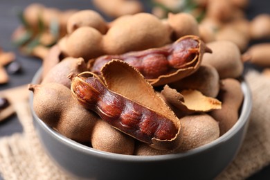 Delicious ripe tamarinds in ceramic bowl on table, closeup