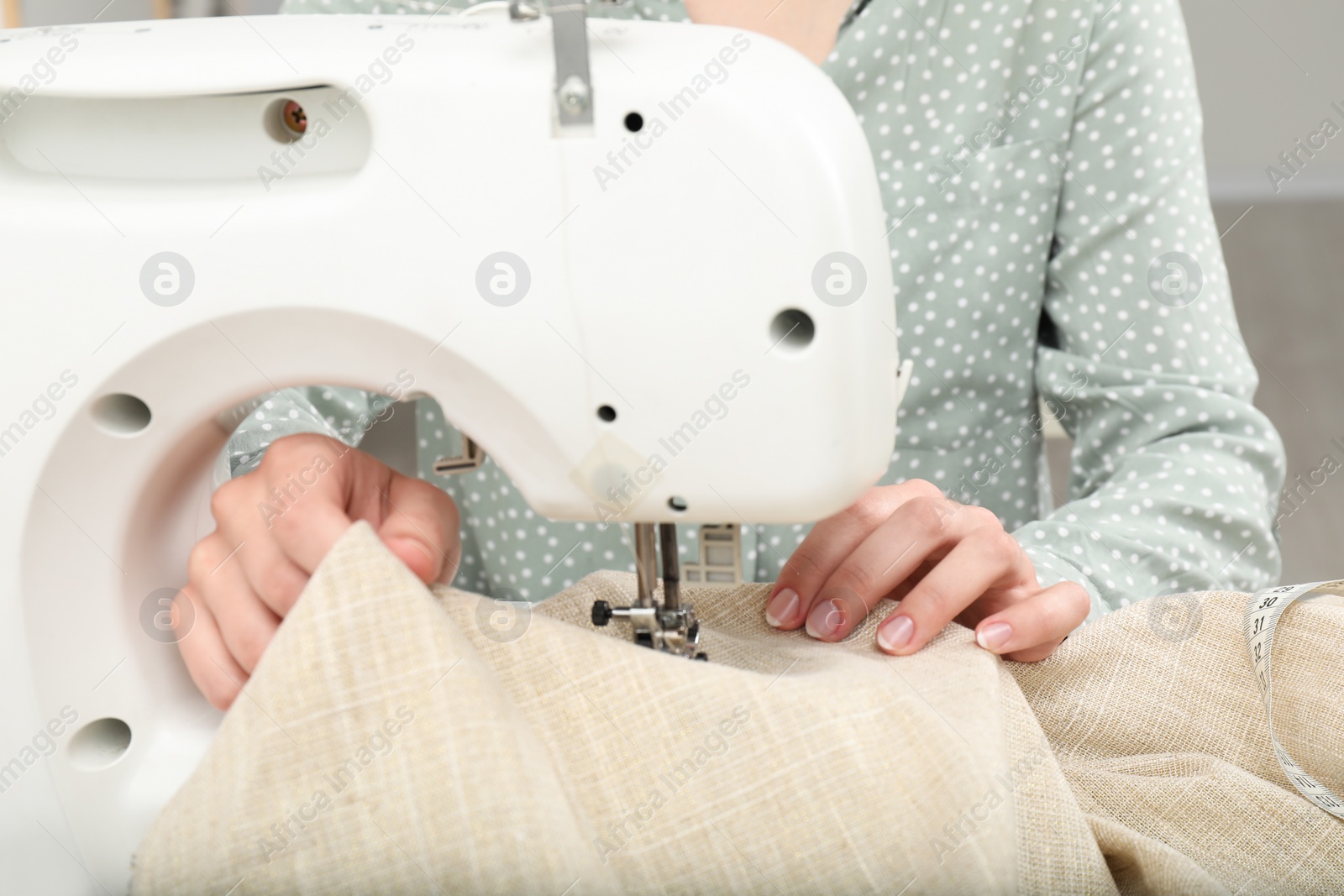 Photo of Seamstress working with sewing machine indoors, closeup